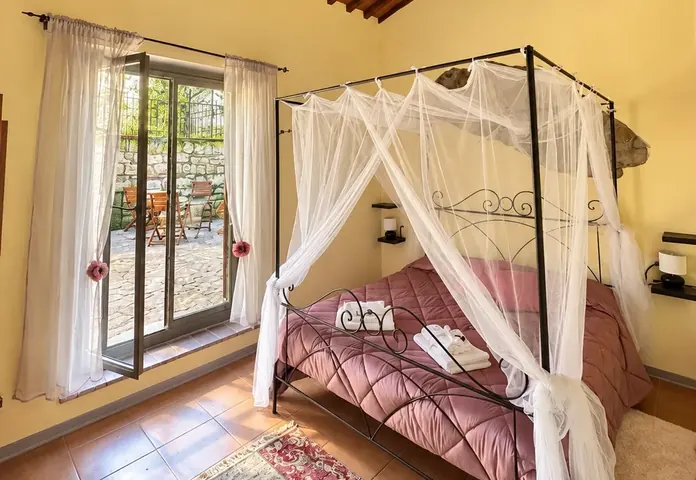 Madame Romantica room: four-poster canopy bed and French window onto the patio